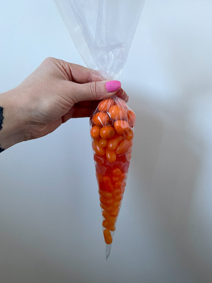 Hand holding orange candy in a candy cone bag