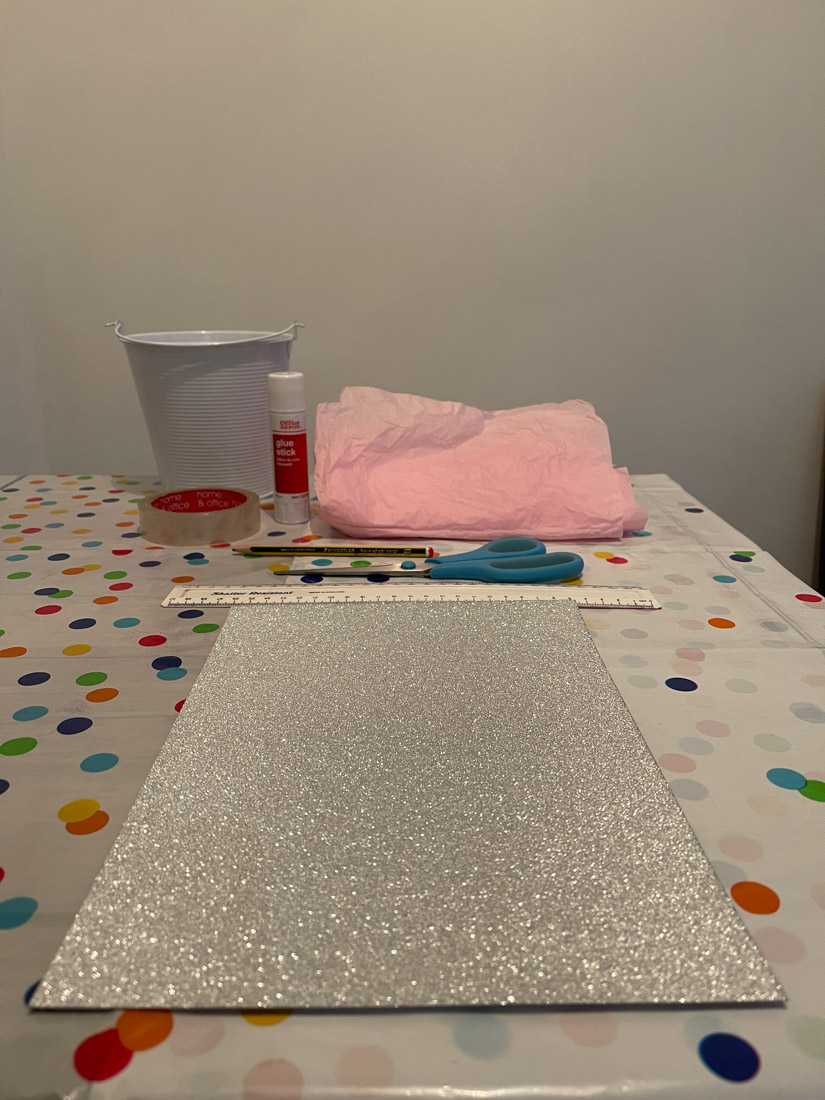 A4 silver glitter card, ruler, pink tissue on a craft table