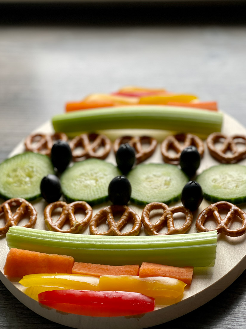 Vegetables placed on oval charcuterie board with vegetables laid out like easter egg design 